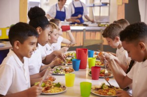 Primary school kids eating at a table in school cafeteria