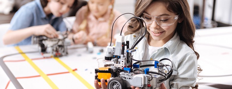 Lovely little girl holding robot at school