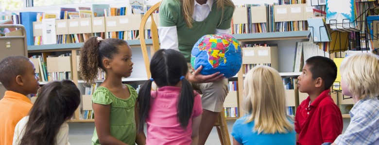 Kindergarten teacher and children looking at globe